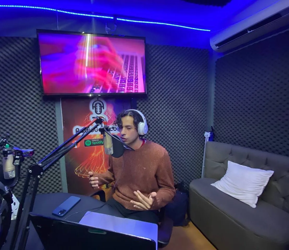 Locutor con audífonos frente al micrófono en la cabina de Radio Galo, con luz azul y morada