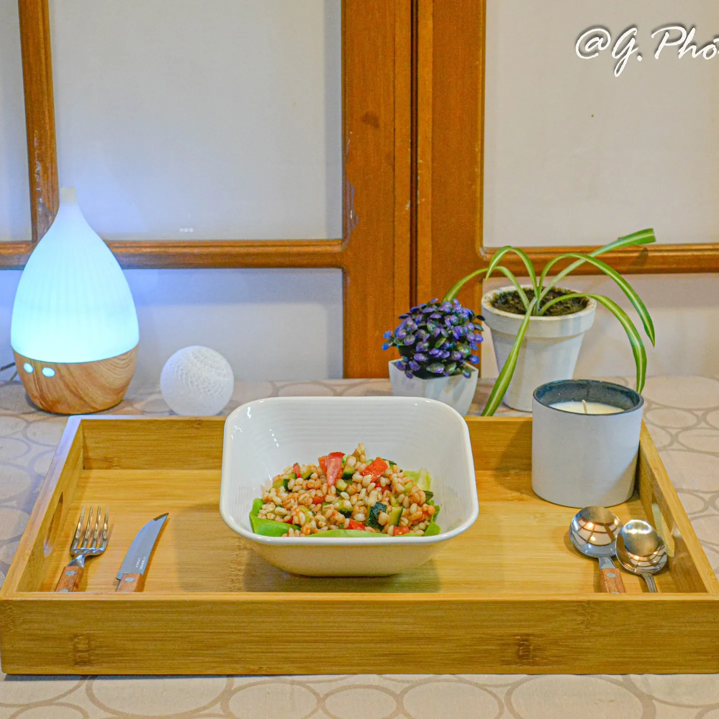 Ensalada en tazón sobre una charola de madera junto a la ventana