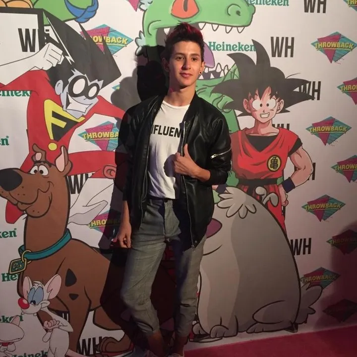 Invitado posando frente a un muro de personajes en un evento