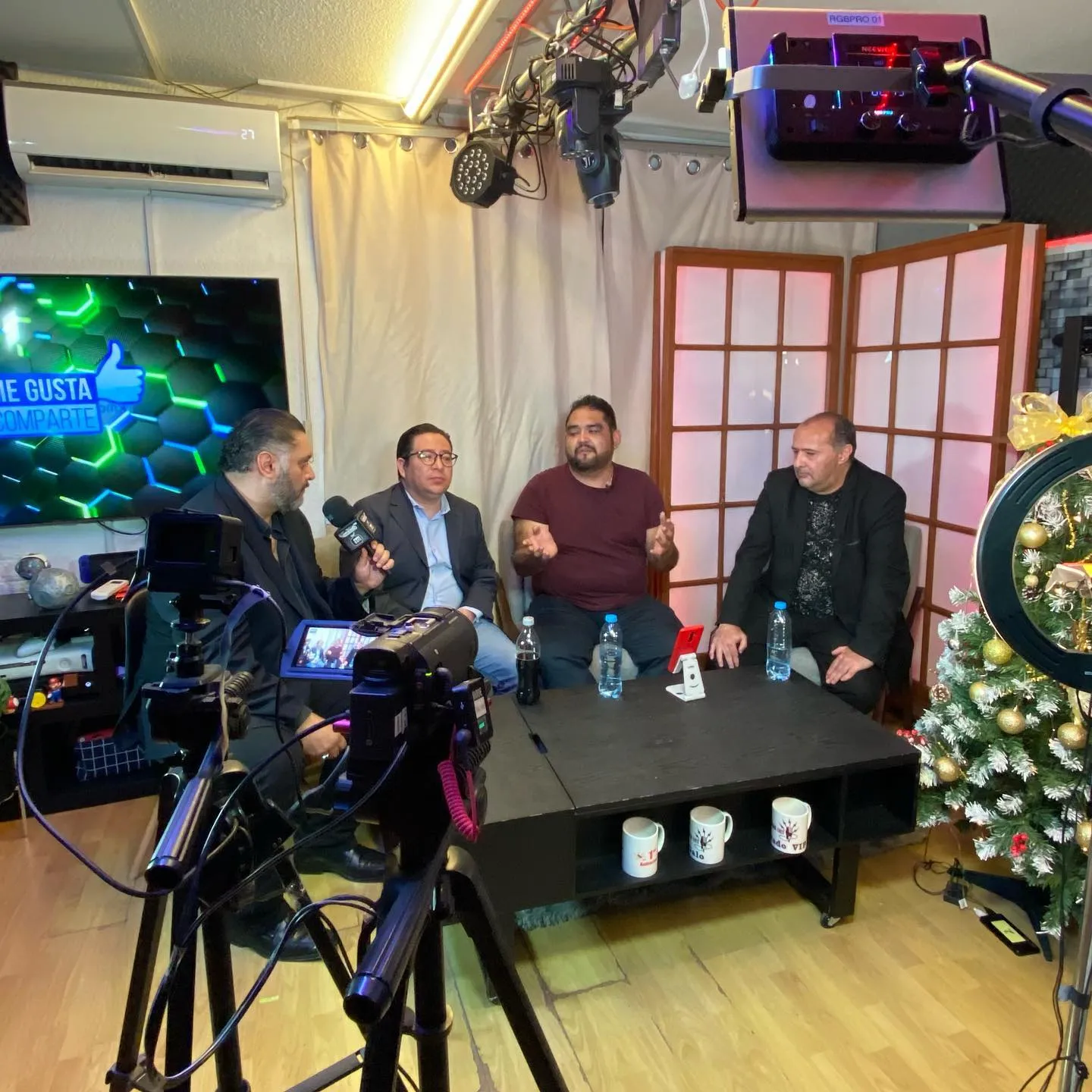 Cámara en primer plano grabando a cuatro invitados en el foro