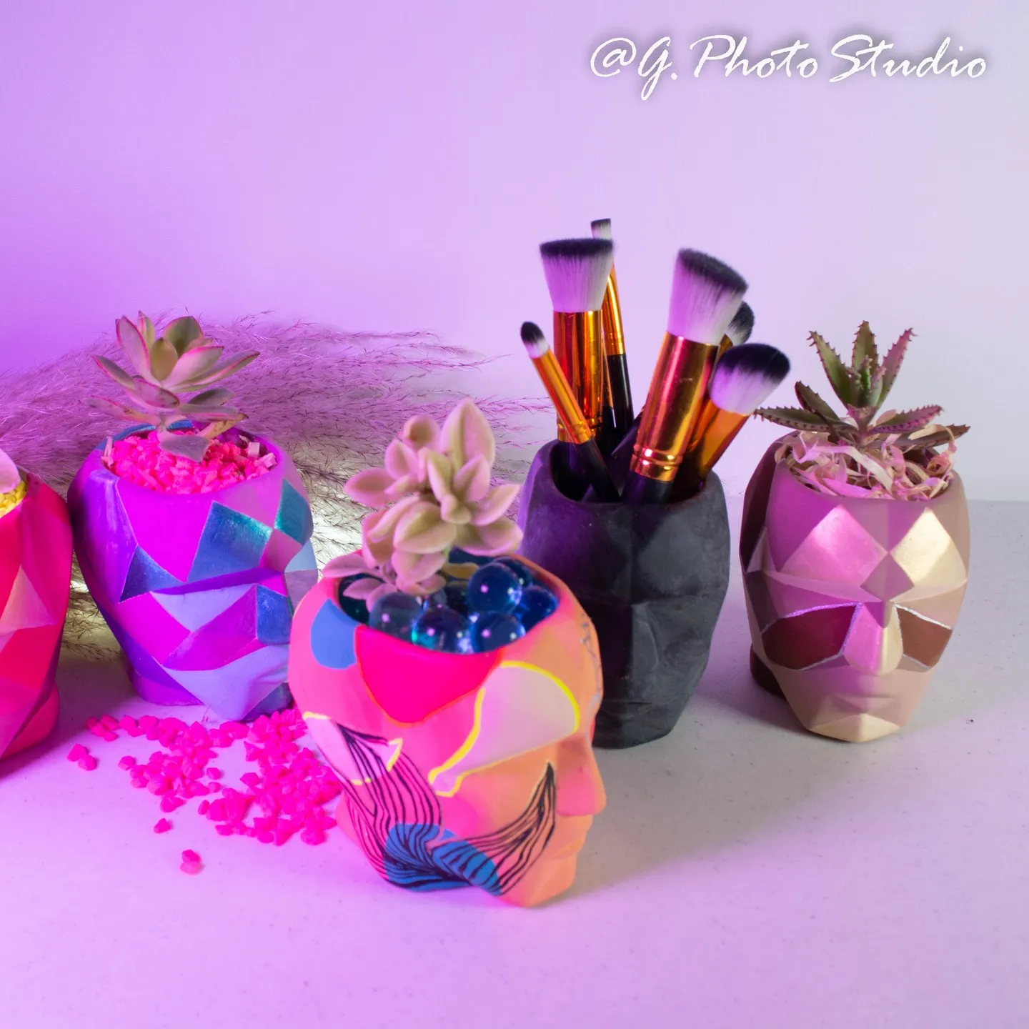 Brochas de maquillaje en macetas geométricas con luz rosa
