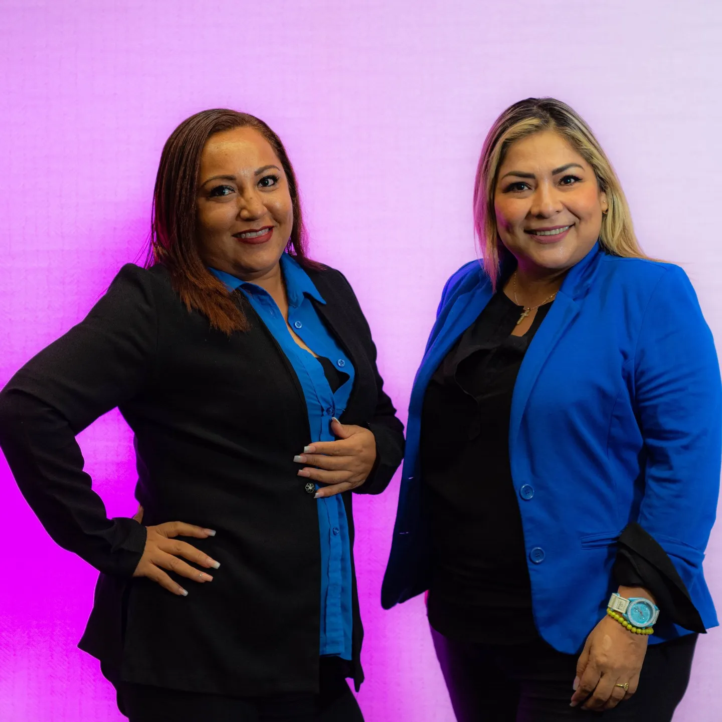 Retrato corporativo de dos mujeres con saco sobre fondo iluminado de magenta