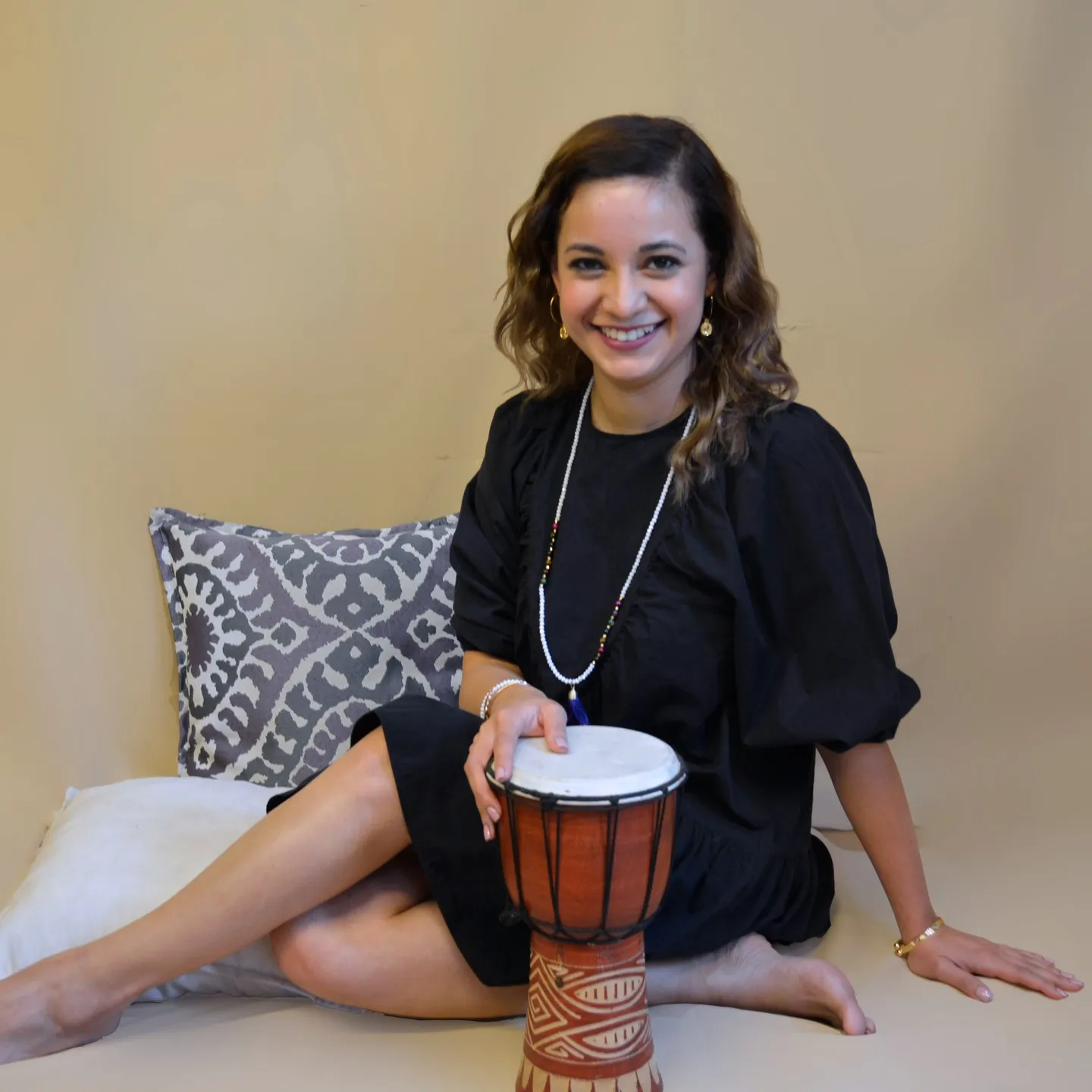 Mujer sonriente sentada con un tambor africano en el estudio