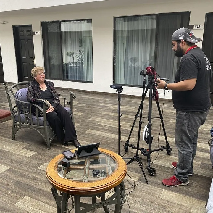 Camarógrafo preparando una entrevista en locación con cámara y tripié