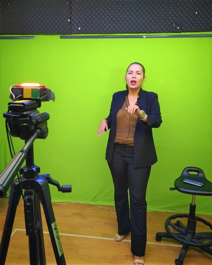 Presentadora grabando frente a una pantalla verde con cámara y luces